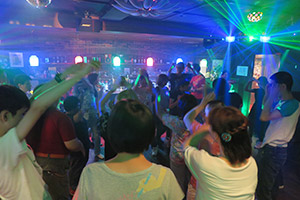 写真:様々な色のライトの中踊る人々