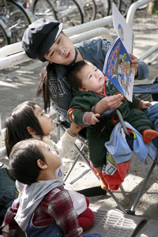 写真：小さな子どもに本を読む女性